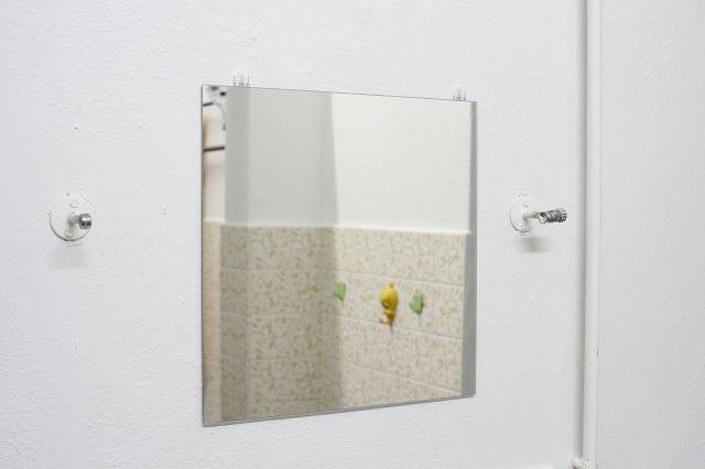 white wall with a piece of BLODL├ûNN mirror, flanked by metal support arms for the old mirror